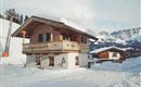 A charming chalet in the snow with mountains in the background. The surroundings are wintry and tranquil.