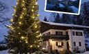 Ein winterliches Szenario mit einem festlich beleuchteten Weihnachtsbaum vor einem gemütlichen Haus im Schnee. Im Hintergrund ist eine Berglandschaft zu sehen.