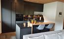 Modern, elegant kitchen with dark furniture and a central wood island. The rooms are designed to be bright and inviting.