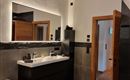 A modern bathroom with a wooden ceiling and elegant furnishings. There is a large sink, a bathtub, and a shower.