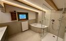 Ein modernes Badezimmer mit einer Dusche und einer Badewanne. Die Holzdetails und das Fenster sorgen für eine gemütliche Atmosphäre.
