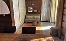 Een moderne interieur met lichte muren en houten accenten. Een eettafel, een bank en een comfortabele stoel zijn zichtbaar.