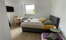 Een lichte kamer met een groot bed en een gezellige zithoek. Er is een tafel en een bank, evenals een televisie aan de muur.