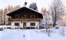 A charming snow-covered house surrounded by a winter landscape. Trees and a tranquil atmosphere give the image an idyllic mood.