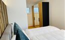 A modern bedroom with a large bed and an elegant wardrobe. The rooms are designed to be bright and friendly.