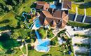 A large complex with several swimming pools and slides surrounded by green meadows. The building has an attractive architecture and invites relaxation.
