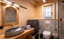Een moderne badkamer met houten wanden en elegante fittingen. Het bevat een wastafel, toiletten en een douche.