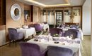 An elegant restaurant with modern furniture and set tables. The walls are designed with warm wood tones and stylish accents.