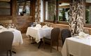 An elegant restaurant with decorated tables and stylish chairs. Large windows provide plenty of daylight and a cozy atmosphere.