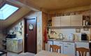 A cozy kitchen with wooden cabinets and a large table. A skylight provides plenty of daylight.