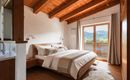Ein modernes Schlafzimmer mit Holzdecke und großen Fenstern. Der Raum ist hell und lädt zur Entspannung ein und bietet eine schöne Aussicht auf die Landschaft.