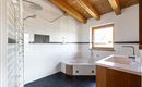 Ein modernes Badezimmer mit einer Dusche und einer Badewanne. Die Holzbalkendecke verleiht dem Raum eine warme Atmosphäre.
