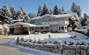 Our house in the snow, surrounded by snow-covered trees.