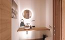 Ein modernes Badezimmer mit einer Holzoberfläche und einer runden Spiegelleuchte. Die Einrichtung ist minimalistisch mit einem Waschbecken und einer toilet.