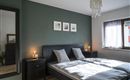 Een moderne slaapkamer met een tweepersoonsbed en zachte kleuren. Er zijn nachtkastjes met lampen en foto's aan de muur.