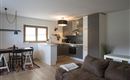 Een moderne woning met een open keuken en een eetgedeelte. De ruimte is licht en vriendelijk ingericht met een comfortabele bank.
