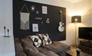 Een stijlvolle woonkamer met een donkere muur, decoratieve elementen en een comfortabele bank. Een gitaar en een lamp geven de ruimte een uitnodigende sfeer.
