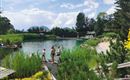 Ein Naturbad mit klaren Wasser und viel Grün. Menschen genießen die Sonne und die Umgebung.