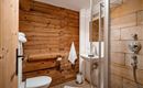 Ein modernes Badezimmer mit Holzpaneelen und einer Dusche aus Glas. Die Einrichtung ist schlicht und sauber.