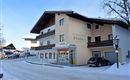 A cozy building in the snow that serves as a guesthouse. The surroundings are wintry with snow-covered streets and trees.
