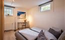 Flauschiges und modernes Schlafzimmerbett mit großem Schrank für das gesamte Reisegepäck und kleinem Arbeitstisch.