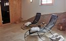Ein entspannender Wellnessbereich mit Liegen und sanfter Beleuchtung. Die Holzverkleidung und der Türbereich schaffen eine gemütliche Atmosphäre.