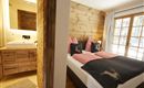 Ein gemütliches Schlafzimmer mit Holzverkleidung und einem modernen Badezimmer. Die Fenster bieten viel Licht und einen schönen Ausblick.