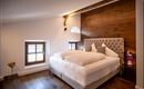 A cozy bedroom with a large, comfortable bed and wood decor on the wall. The room has large windows that provide plenty of daylight.