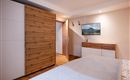 Ein modernes Schlafzimmer mit einem großen Bett und einem Holzschrank. An der Wand hängt ein Bild von einer Landschaft.