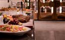 A refined buffet with various dishes, including meat, meat dishes, and fresh vegetables.  
The table is elegantly set and offers an inviting atmosphere.