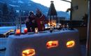 Ein gemütlicher Außenbereich mit einer Schneebar und stimmungsvollem Licht. Zwei Personen stehen zusammen und genießen die winterliche Atmosphäre in den Bergen.