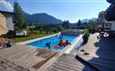 Ein schöner Pool in einer sonnigen Landschaft. Menschen genießen das Wasser und die Aussicht auf die Berge.