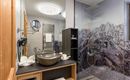 A modern bathroom with a large stone sink and an elegant shower cabin. The walls are decorated with a beautiful mountain motif.