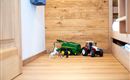 A toy landscape with a green tractor, a red tractor, and some plastic figures. The floor is made of wood and the wall is painted light.