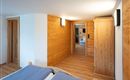 A cozy room with wooden walls and modern design. The room features a double bed and a large wardrobe.