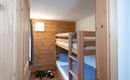 A cozy children's room with a wooden bunk bed. There are toys on the floor and soft, blue bedding.