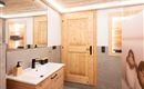 A modern bathroom with a wooden door and a white sink. The walls are light with warm wood elements and gentle lighting.