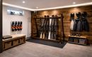 Een stijlvolle skikamer met ski's, skischoenen en helmen aan de muur. De houten bekleding en heldere verlichting creëren een gezellige sfeer.
