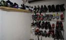 Ein Raum mit verschiedenen Ski- und Snowboardschuhen, die ordentlich an einer Wand hängen. Oben ist ein Regal mit weiteren Paaren von Schuhen.