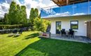 A modern house with a balcony and a cozy terrace. The garden is green and inviting, perfect for relaxation.