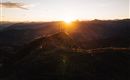 A breathtaking sunset over the mountains. The silhouettes of people stand on a peak, enjoying the view.