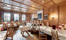 Ein gemütliches Restaurant mit Holzdekor und festlich gedeckten Tischen. Im Raum sind traditionelle Elemente und eine warme Atmosphäre zu sehen.