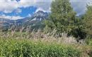 Een schilderachtig landschap met hoge bergen op de achtergrond en weelderig groen op de voorgrond. De wolken aan de hemel geven de scène een vredige sfeer.