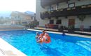 Ein einladender Schwimmingpool mit Kindern, die auf einem aufblasbaren Spielzeug schwimmen. Im Hintergrund sieht man ein charmantes Haus und die umliegende Landschaft.