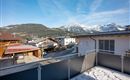 A beautiful view of snow-covered mountains and a picturesque alpine landscape. The sun shines over the rooftops of the houses in the area.