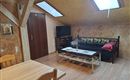 A cozy living space with a table, a sofa, and a television. There are skylights that let in plenty of light.
