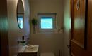 A modern bathroom with a sink, a toilet, and a small window. The room is bright and has a cozy atmosphere.