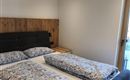 Ein gemütliches Schlafzimmer mit einem Doppelbett und blauen Bettdecken. Der Raum hat einen modernen Look und viel Tageslicht durch ein Fenster.