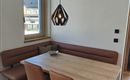 Ein gemütlicher Essbereich mit einem holzigen Tisch und bequemen Stühlen. Eine moderne Pendelleuchte sorgt für angenehmes Licht.