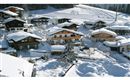 A picturesque village in the snow with traditional chalets and snowy landscapes. The houses are surrounded by a beautiful winter landscape.